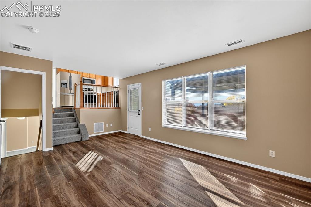 Image 14 of 29: Family room with dark wood finished floors and stairs leading to basement o