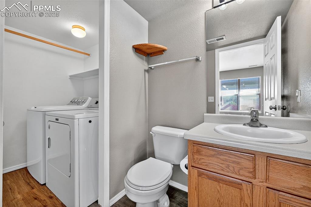 Image 15 of 29: Bathroom with washing machine and dryer, vanity, dark wood-type flooring, a
