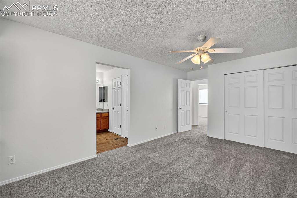Image 18 of 29: Primary bedroom with dark carpet, a textured ceiling, ceiling fan, a closet