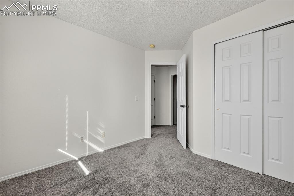 Image 24 of 29: Unfurnished bedroom featuring a textured ceiling, carpet flooring, and a cl