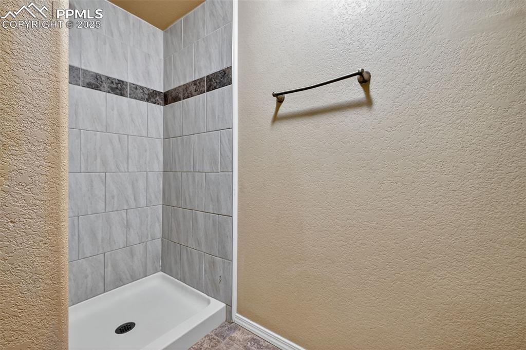 Image 29 of 29: Full bath with a textured wall and a stall shower