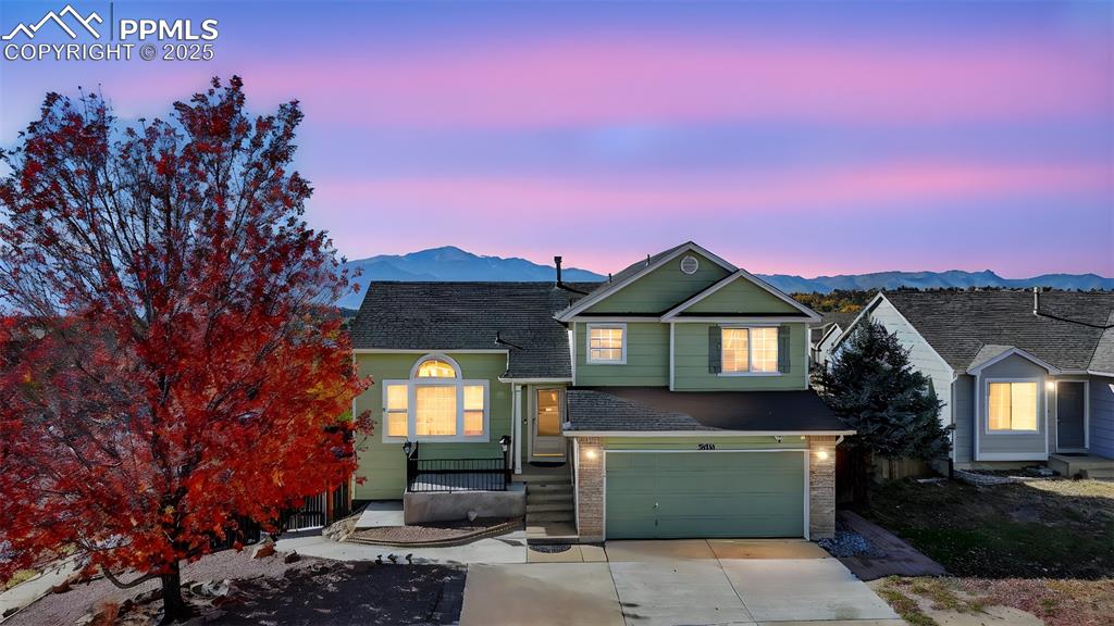 Image 5 of 29: View of front of property with a garage, concrete driveway, and a mountain 