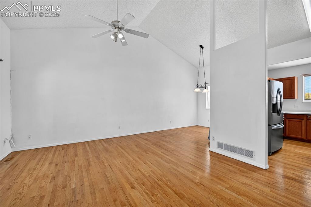 Image 7 of 29: Living room featuring a textured ceiling, light wood-style flooring, high v