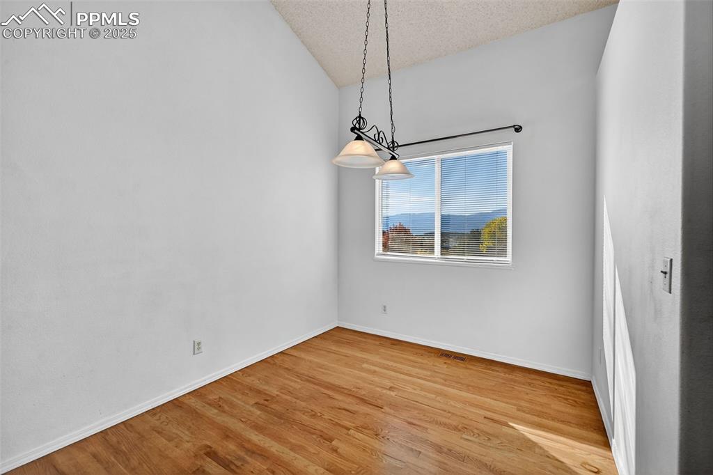 Image 9 of 29: Dining area featuring vaulted ceiling, light wood-style flooring, and a tex