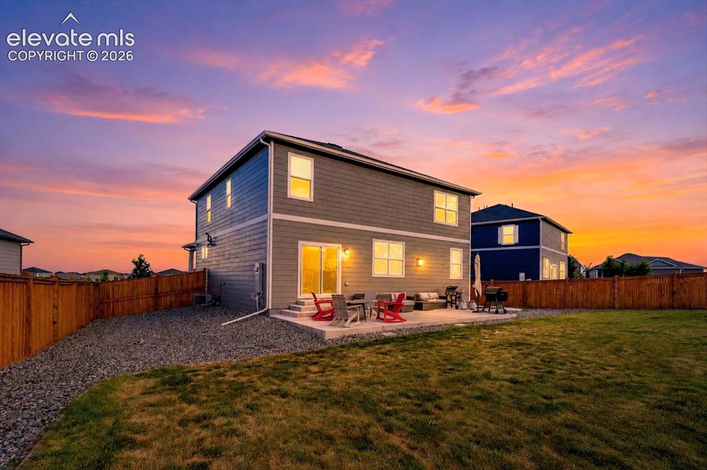 Image 2 of 47: Sunset rear view of home and backyard.