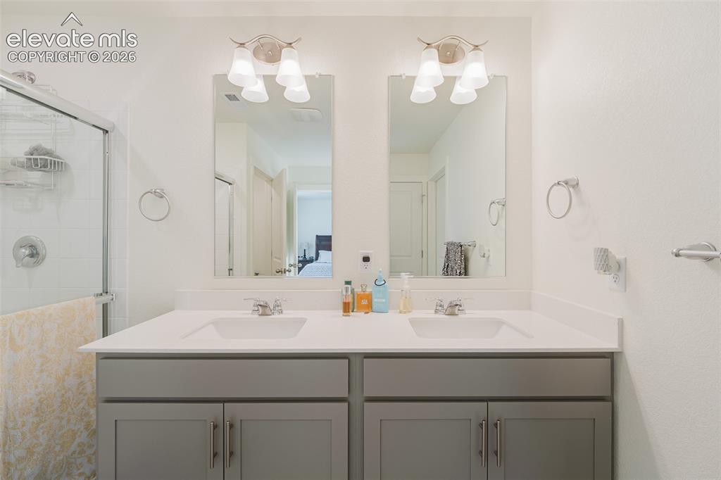 Image 29 of 48: Upper Level Primary Bathroom with a dual sink vanity, mirrors, and an enclo