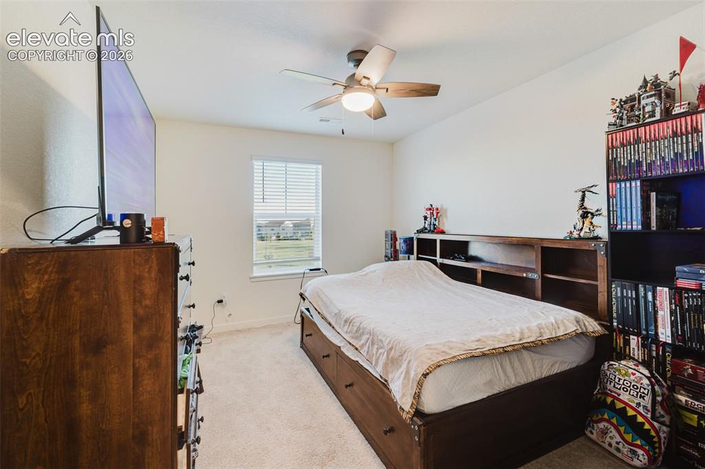 Image 32 of 48: Upper Level Bedroom #3 with neutral carpet and a lighted ceiling fan.