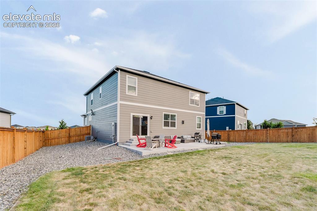 Image 38 of 47: Fenced backyard with auto sprinklers, grassy area, rock beds, and a concret