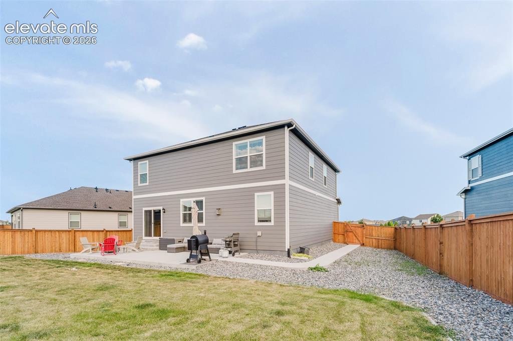 Image 41 of 48: Rear view of fenced backyard, concrete patio, and side yard walkway to the