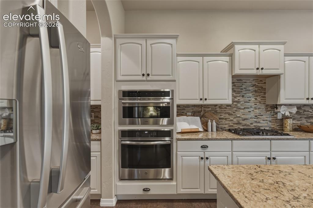 Image 10 of 49: Stainless steel refrigerator, integrated double oven, white cabinetry with 