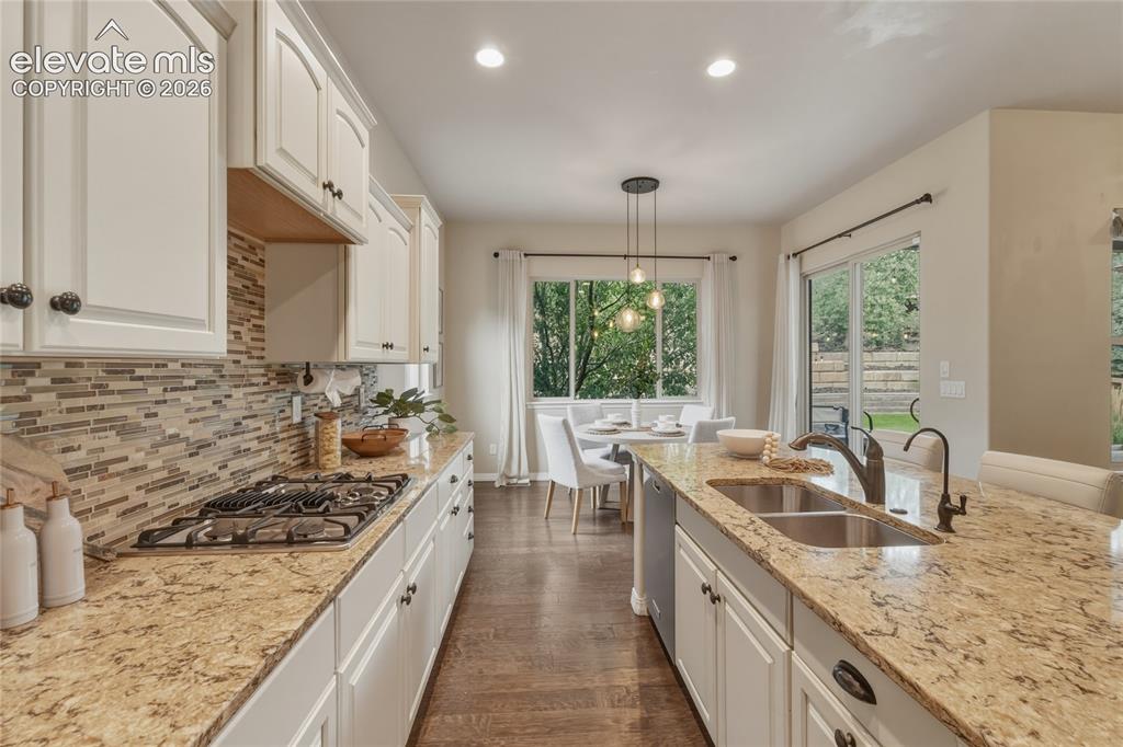Image 11 of 49: Kitchen featuring light-toned cabinetry, granite countertops, a tiled backs