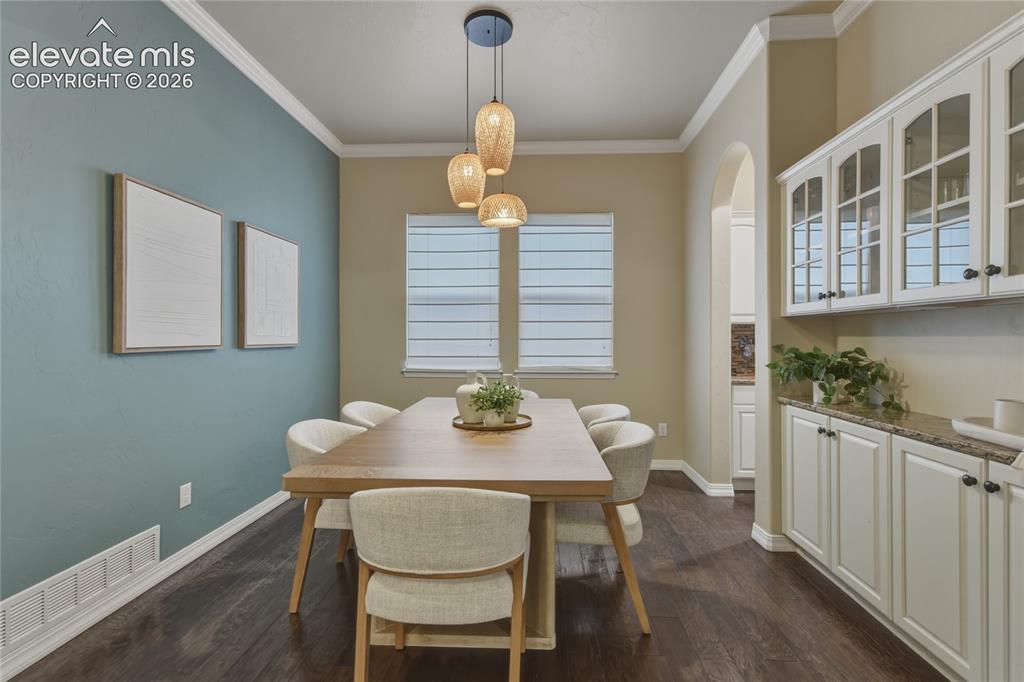 Image 13 of 49: Dark wood-finish flooring, white crown molding, pendant lighting, built-in