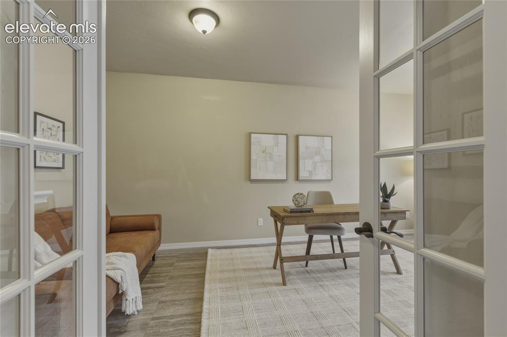 Image 14 of 49: French doors opening into a room with wood-finish flooring and a ceiling-mo
