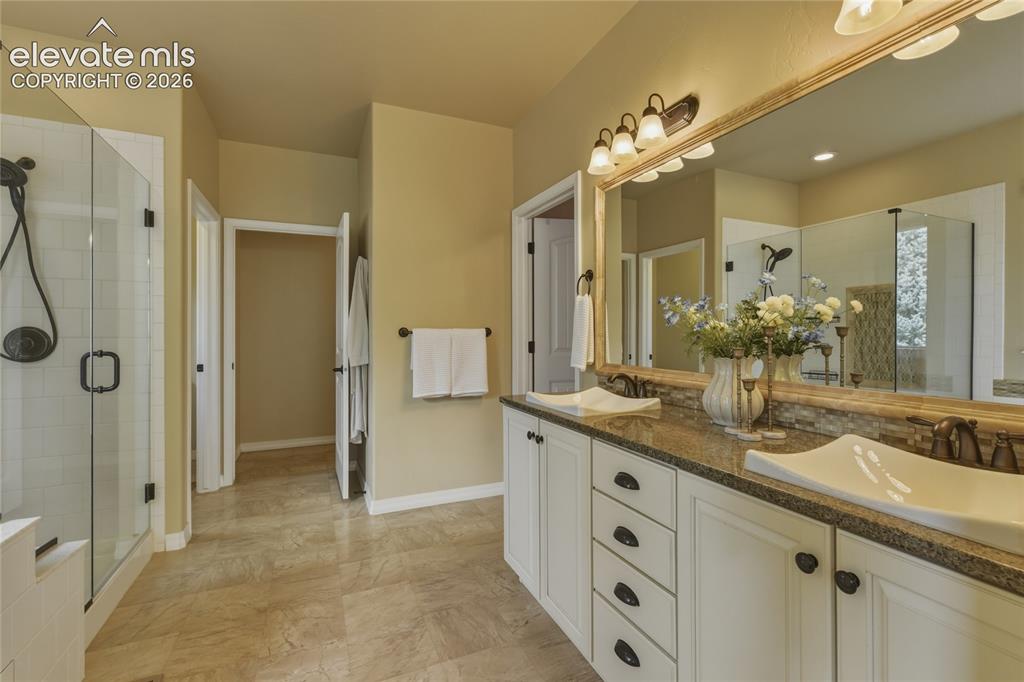 Image 20 of 49: Dual vanity with undermount sinks, granite countertop, and mosaic tile back