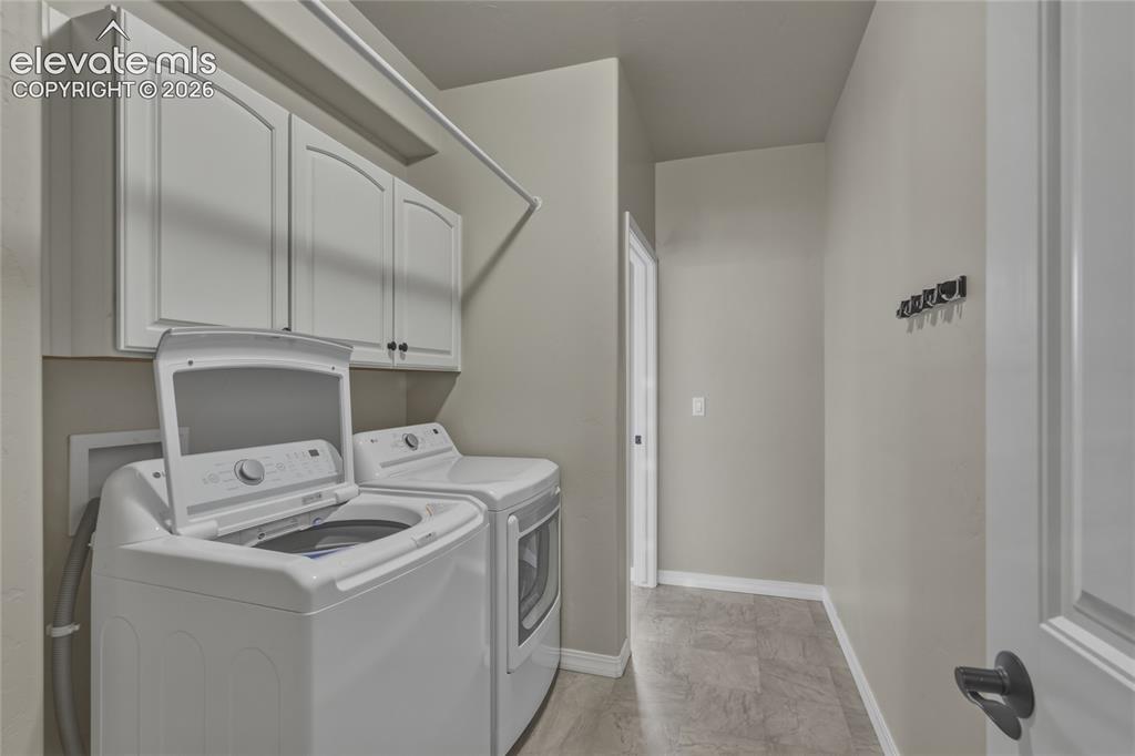 Image 23 of 49: Laundry area featuring upper cabinetry with arched panels, a drying rod, an