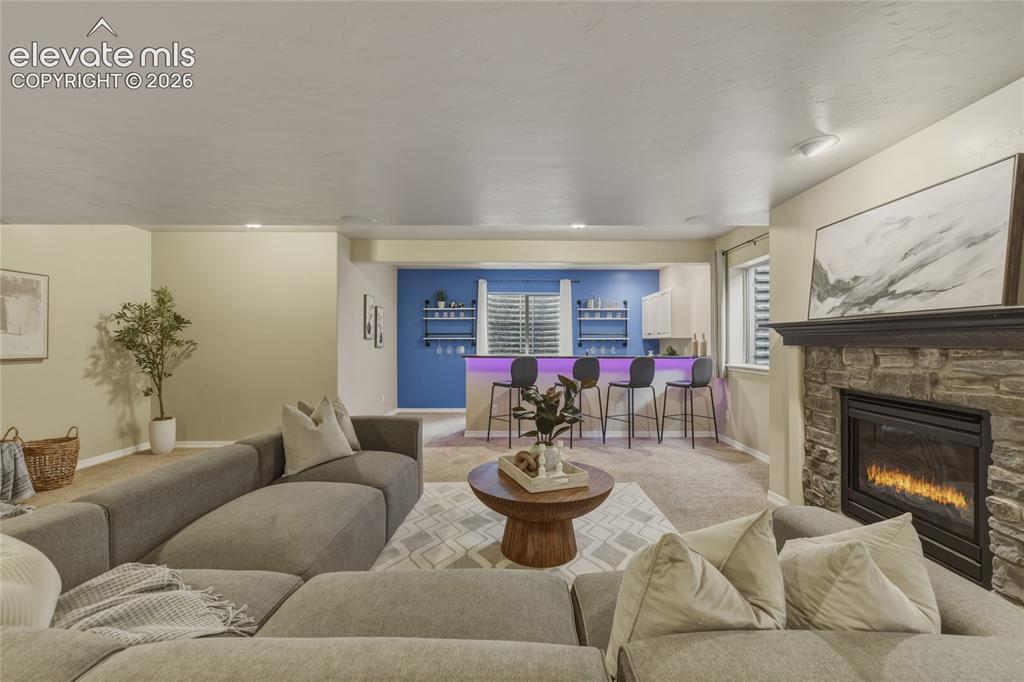 Image 26 of 49: Stacked stone fireplace with a dark wood mantel, recessed lighting, and a b