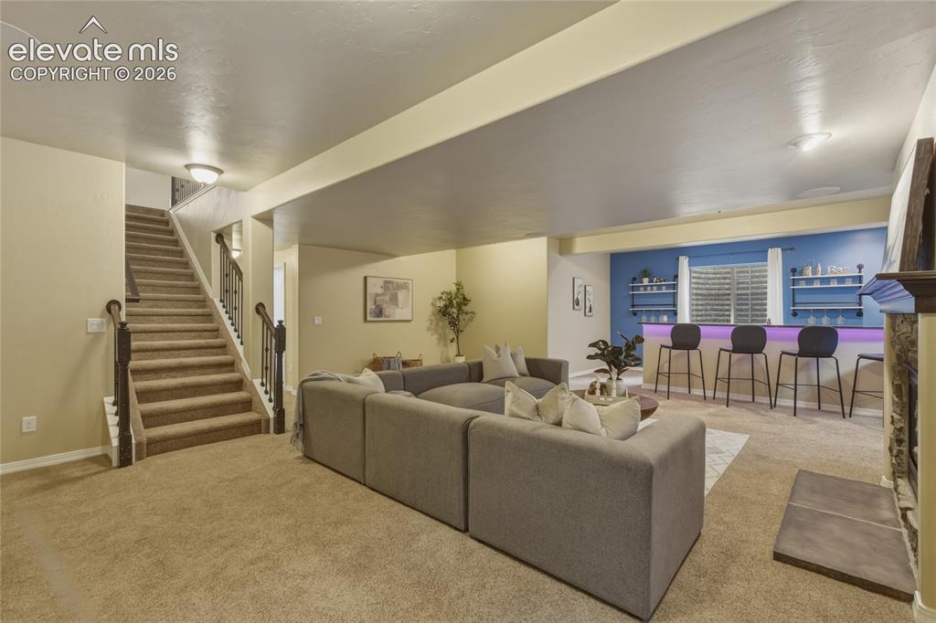 Image 27 of 49: Finished basement with carpeted flooring, a carpeted staircase with dark wo