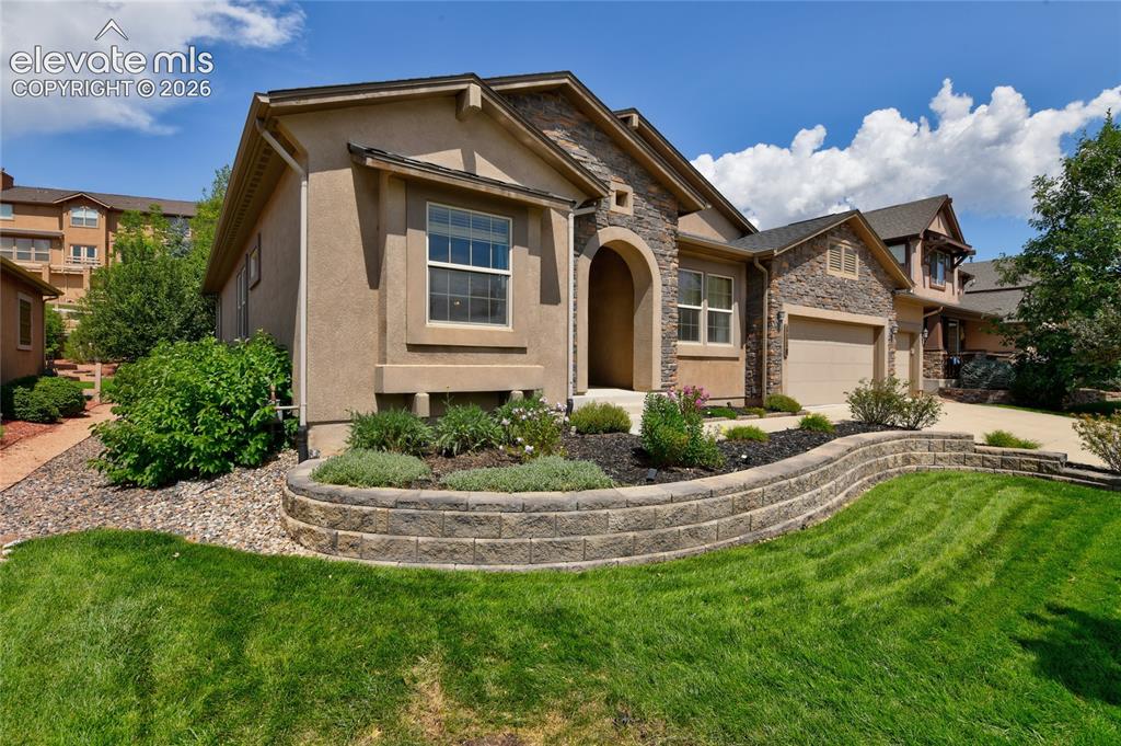 Image 3 of 49: Stone and stucco exterior, arched entry, two-car garage, front yard with re
