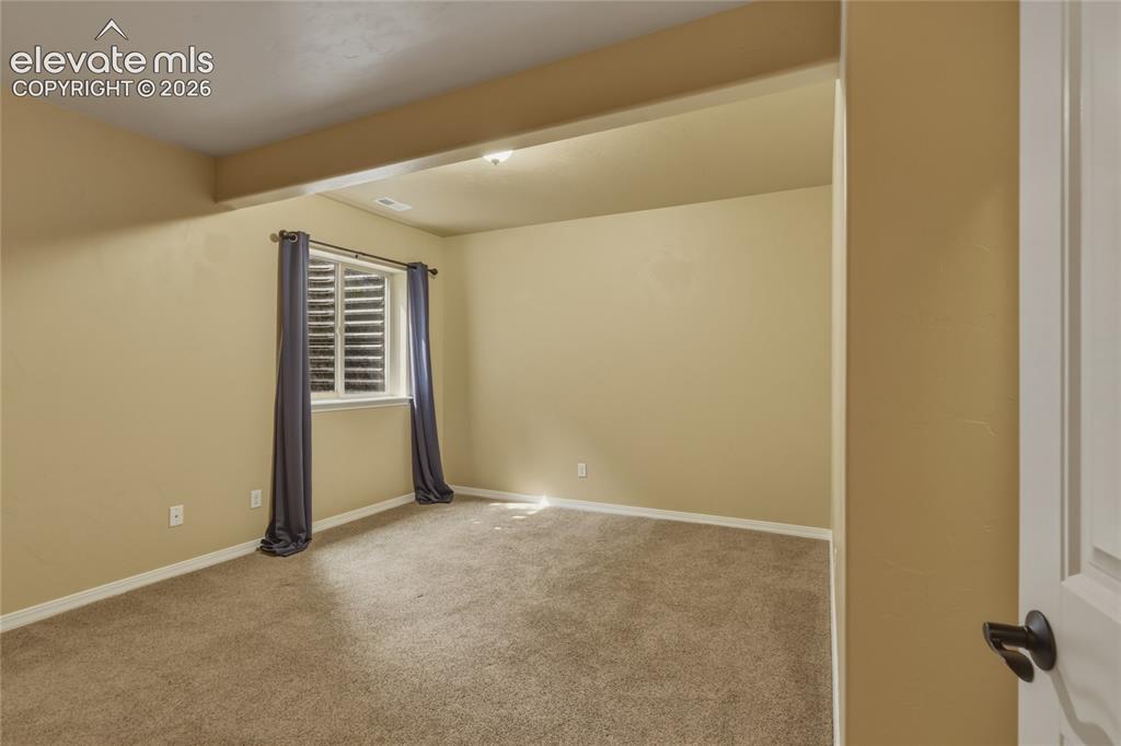 Image 31 of 49: Recessed lighting illuminates this carpeted room, featuring a window with i