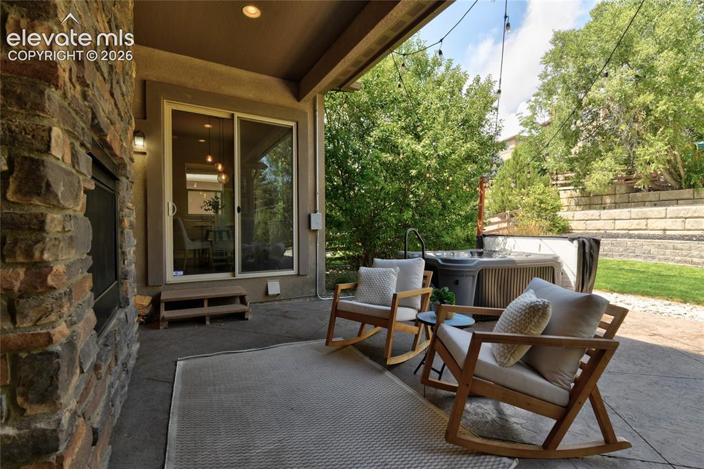 Image 36 of 49: Patio featuring a stone-clad fireplace, sliding glass door, string lighting