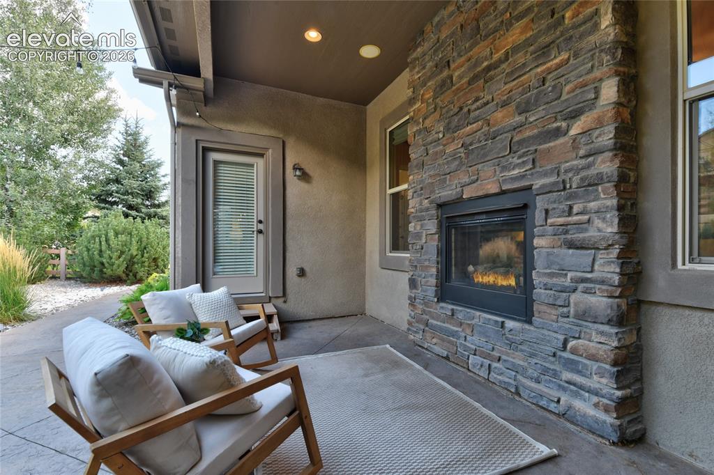 Image 37 of 49: Outdoor patio featuring a built-in stone fireplace, stamped concrete floori