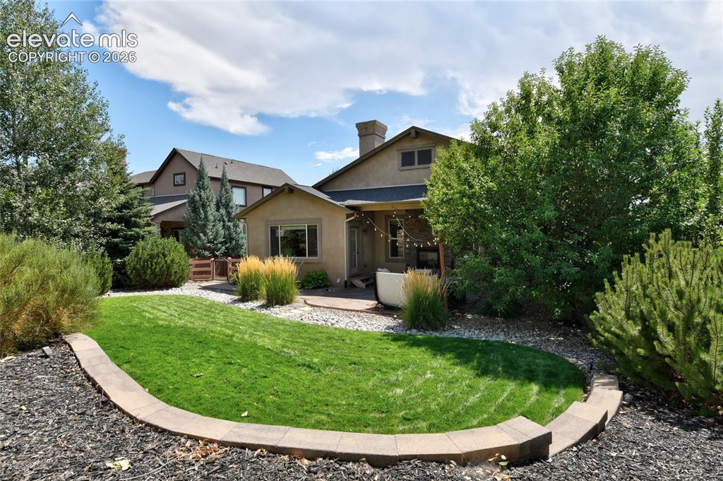 Image 40 of 49: Expansive backyard featuring a manicured lawn, established landscaping, and