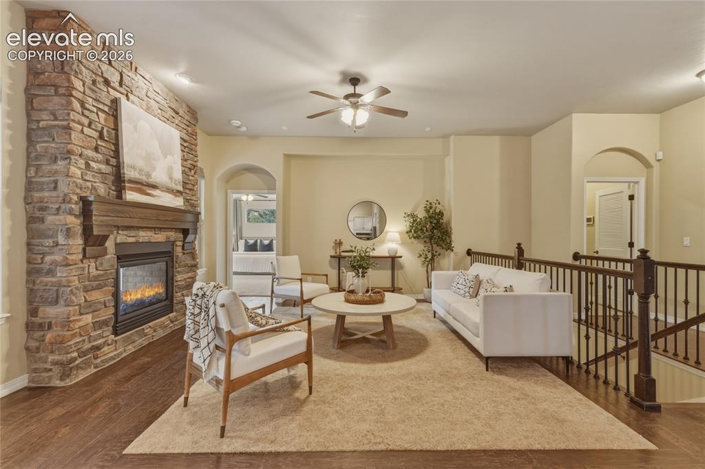 Image 7 of 49: Stone-faced fireplace with a wood-finish mantel, wood-finish flooring, and 