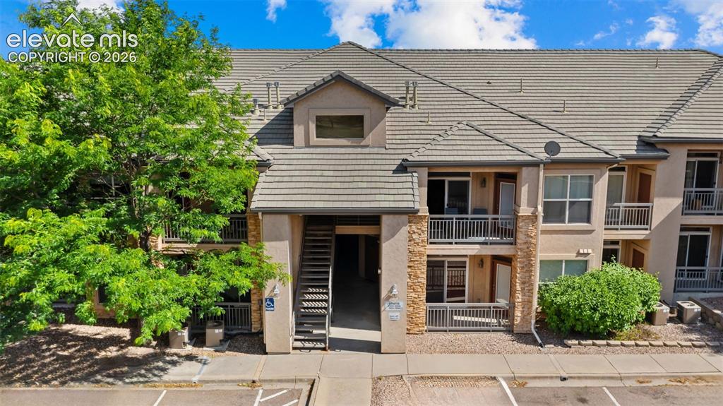 Image 1 of 33: Multi-story residential building featuring a tile roof, stucco facade, and