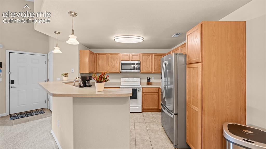 Image 10 of 33: Open-concept kitchen featuring light wood-finish cabinetry, stainless steel