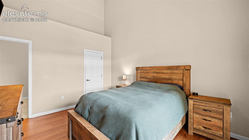 Image 14 of 33: Bedroom featuring vaulted ceilings, wood-finish flooring, and a neutral col
