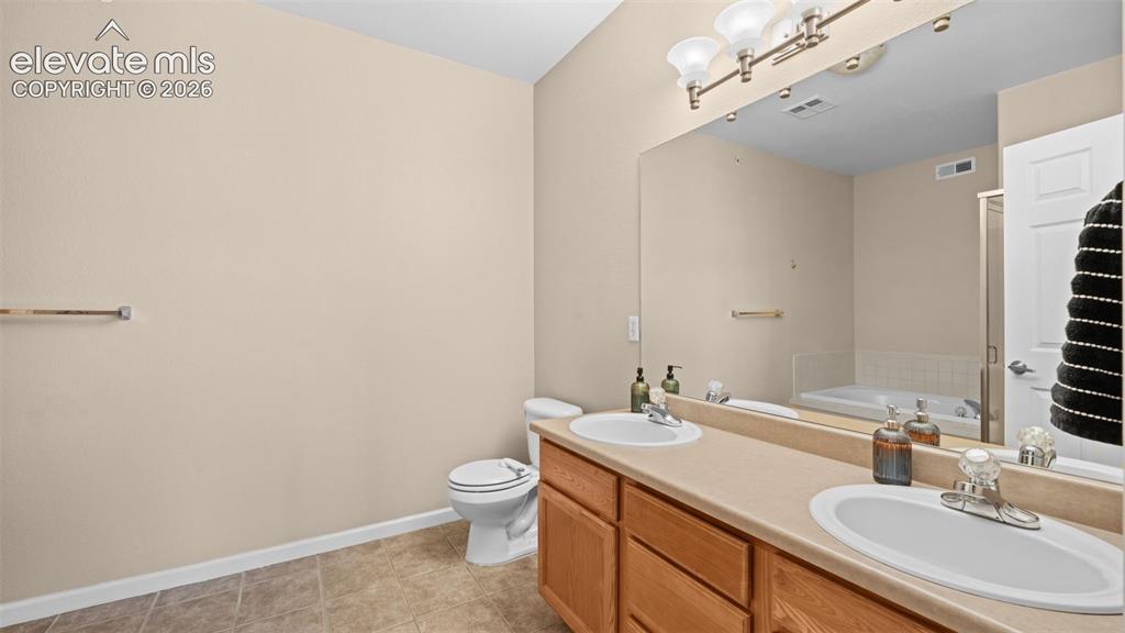 Image 17 of 33: Bathroom featuring a dual vanity with oak-finish cabinetry, integrated sink
