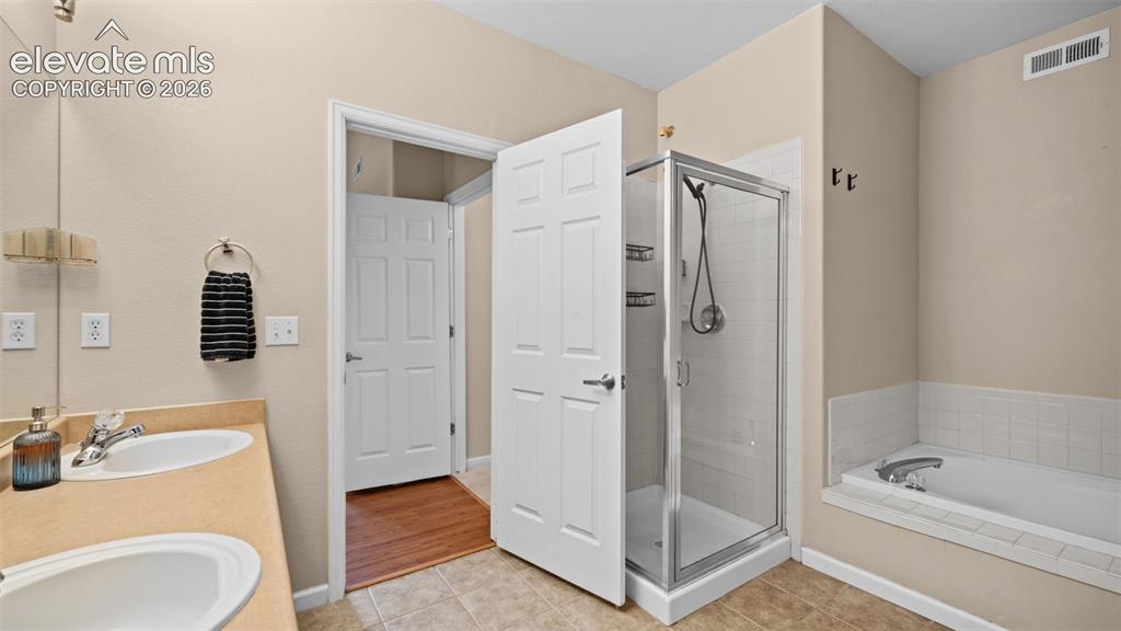 Image 18 of 33: Dual vanity with undermount sinks, a glass-enclosed shower, and a built-in