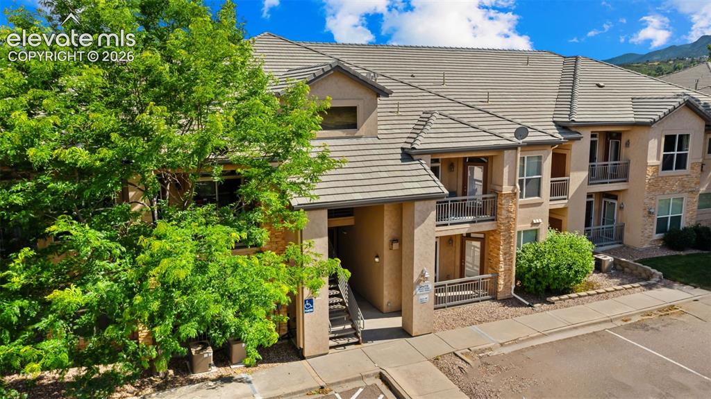 Image 3 of 33: Multi-story stucco exterior featuring stone accents and a neutral tile roof