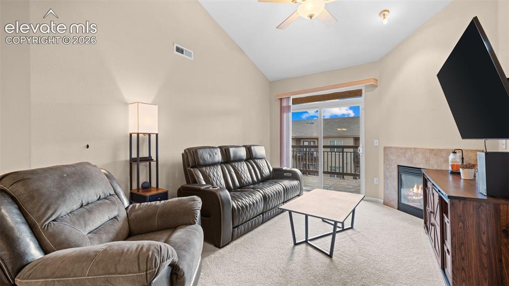 Image 5 of 33: Living area featuring a vaulted ceiling with a ceiling fan, a fireplace wit