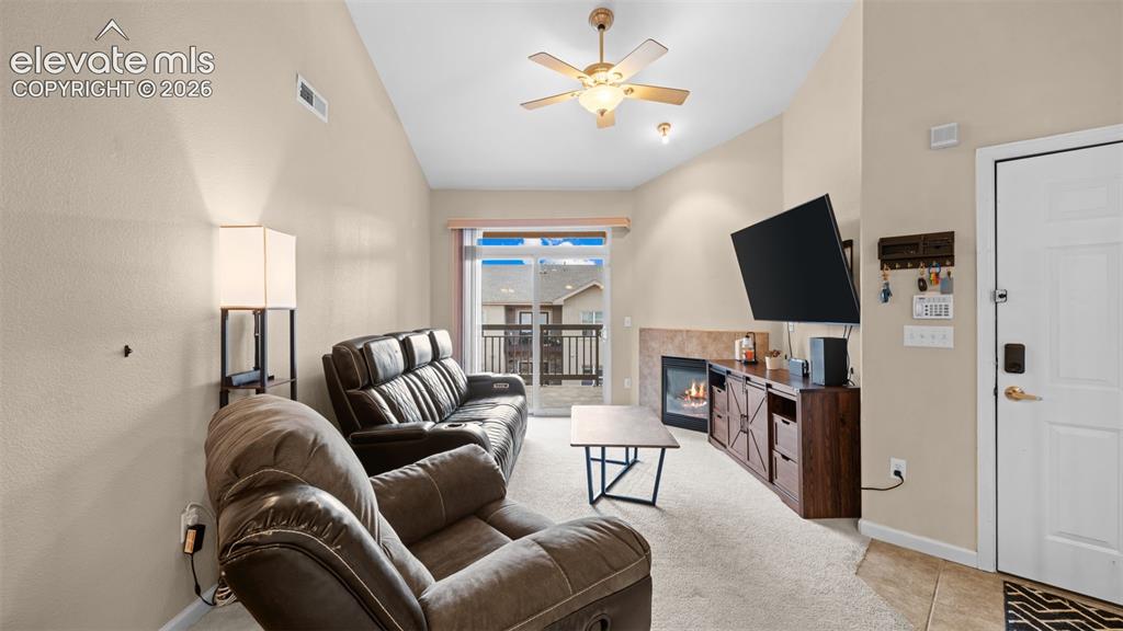 Image 6 of 33: Living area featuring vaulted ceilings, a ceiling fan, a gas fireplace with