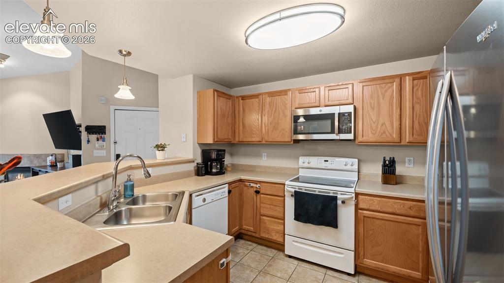Image 9 of 33: Kitchen featuring wood cabinetry, stainless steel sink, and light-colored c