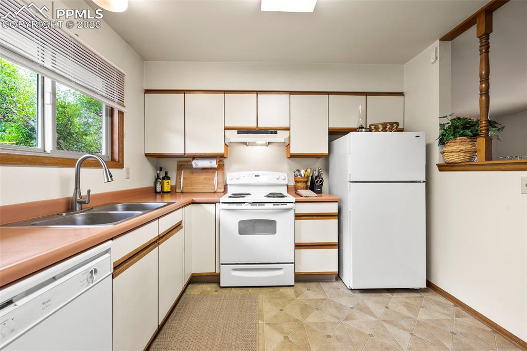 Image 12 of 22: Kitchen window looks out to back deck and natural landscaping.  Lots of nat