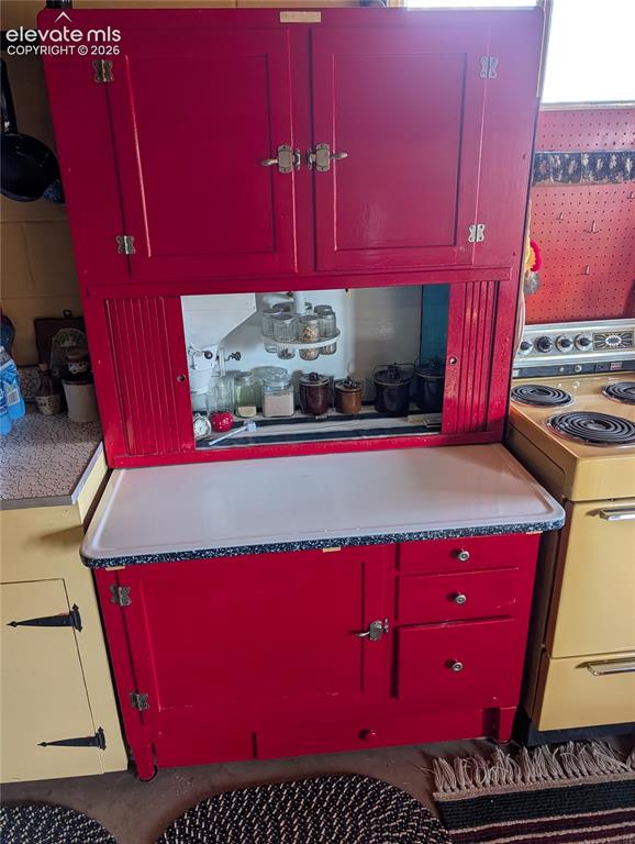 Image 11 of 42: Freestanding red cabinetry with upper storage, a central open shelf, and lo