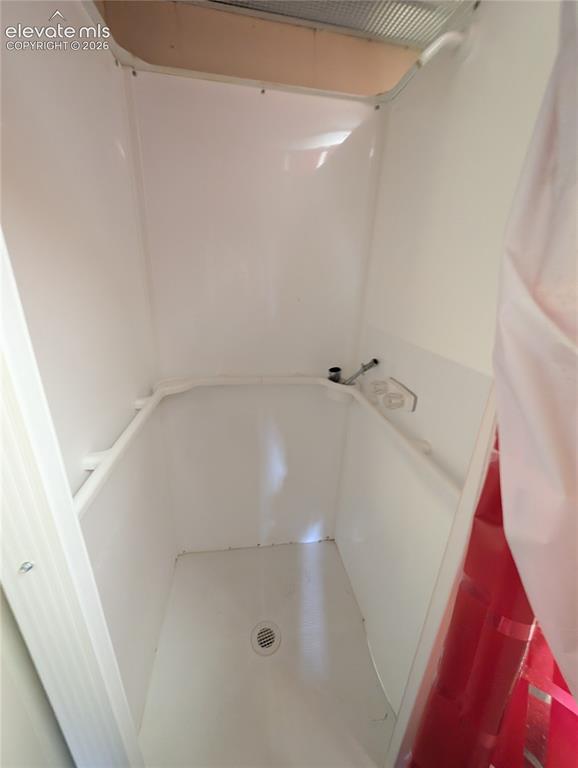 Image 13 of 42: White shower stall with a floor drain