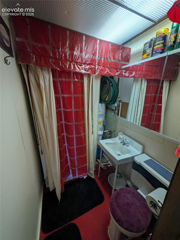 Image 14 of 42: Compact bathroom featuring a white wall-mounted sink, toilet, and red floor