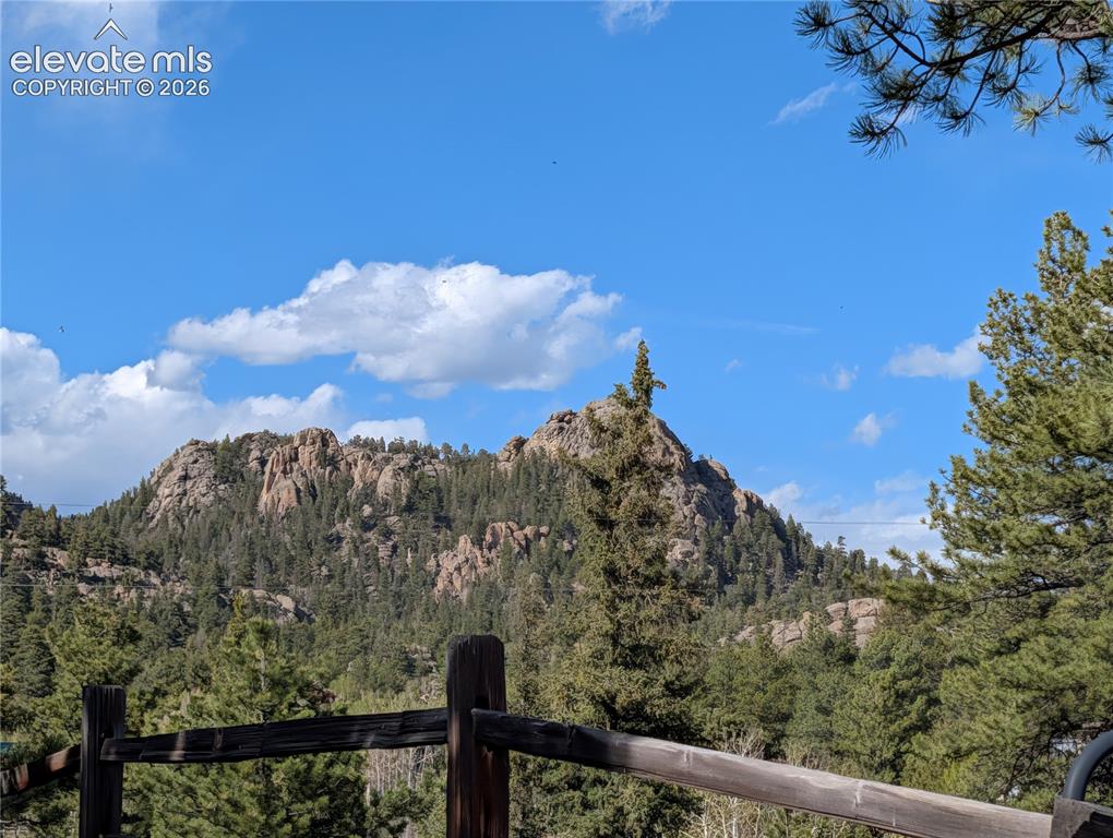 Image 4 of 42: Mountain backdrop with a clear blue sky, featuring a rustic wooden fence in