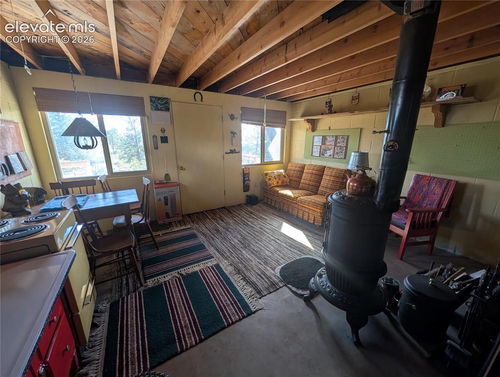 Image 8 of 42: Open-concept living area featuring an exposed timber ceiling, concrete floo