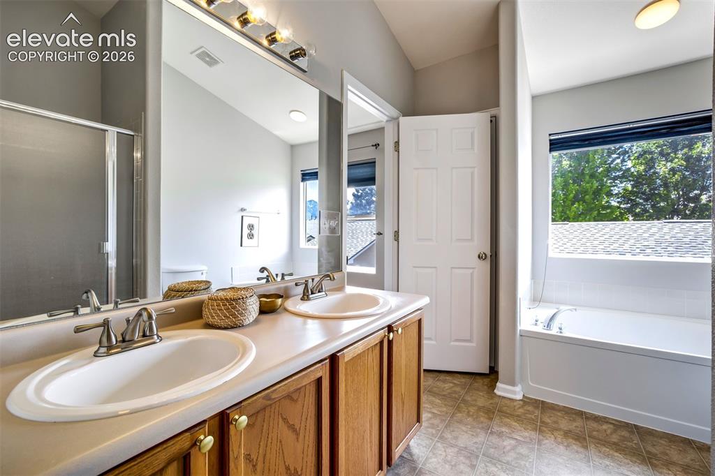 Image 19 of 39: Attached Primary Bathroom with a soaking tub & standing shower. 