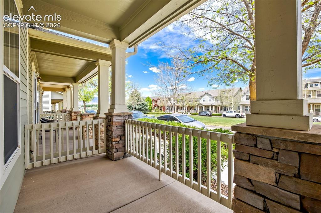 Image 34 of 39: Covered front patio that opens to green space. 