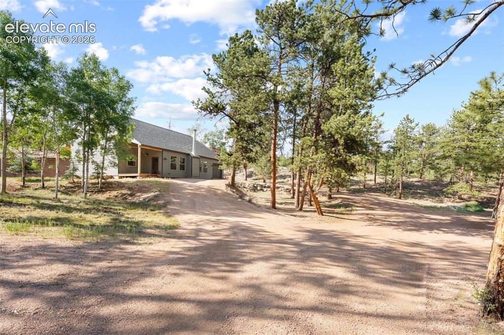 Caption: Contemporary ranch-style residence featuring a covered front porch, grey siding, and a dark shingle 