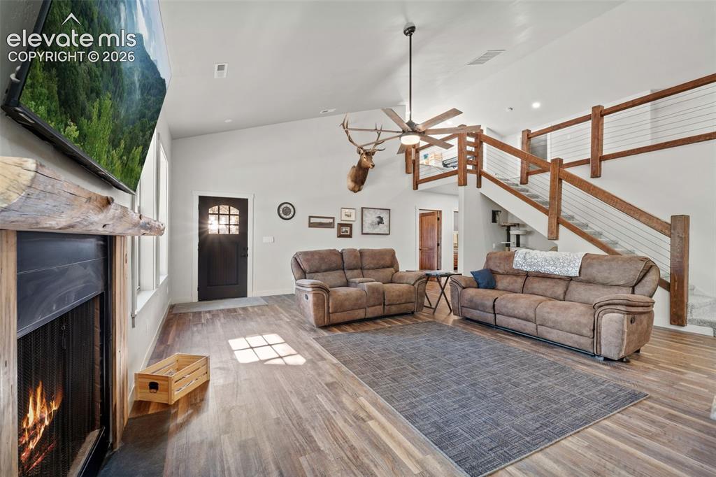 Image 10 of 42: Vaulted ceiling with a ceiling fan, wood-finish flooring, staircase with wo