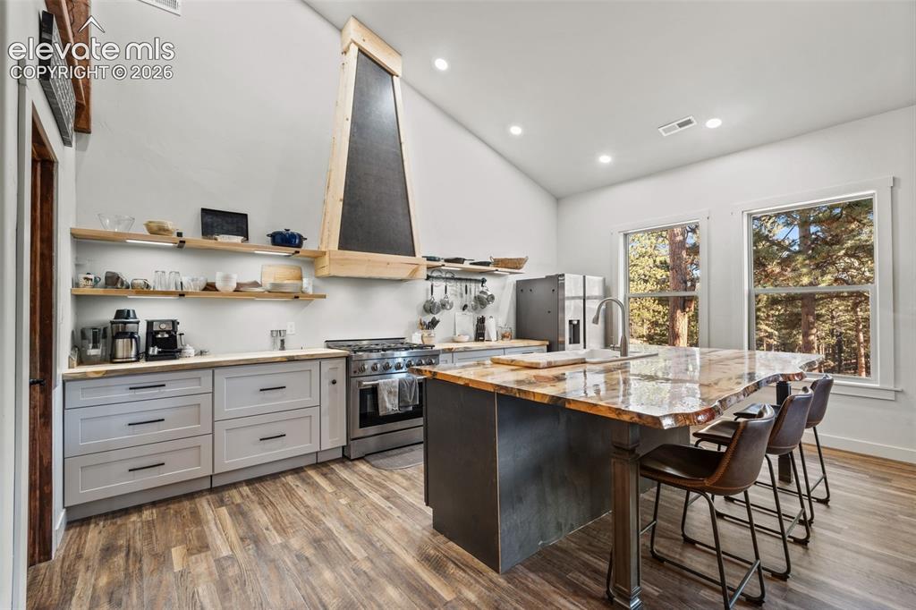 Image 12 of 42: Vaulted ceilings and recessed lighting illuminate a kitchen featuring wood-