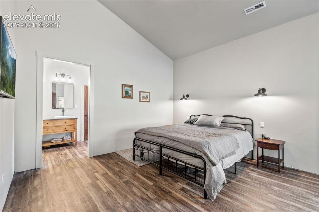 Image 19 of 42: Vaulted ceiling, wood-finish flooring, and wall-mounted sconces