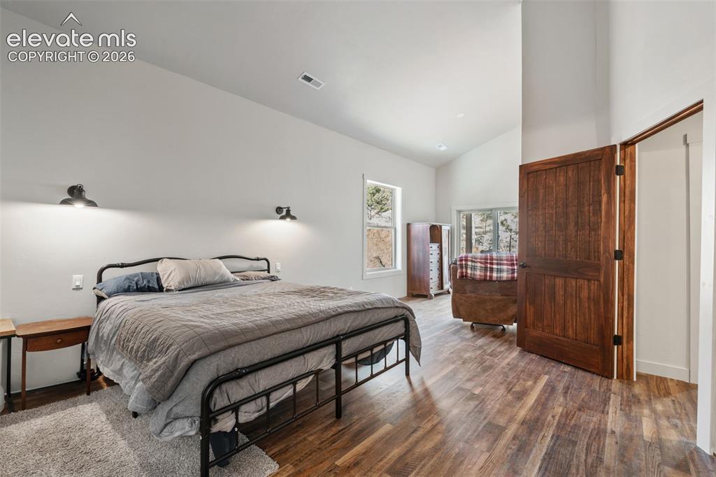 Image 20 of 42: Vaulted ceiling, wood-finish flooring, two large windows, dark wood panel d