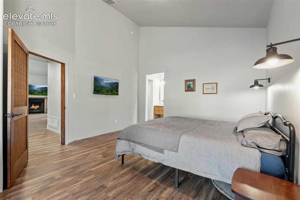 Image 22 of 42: Vaulted ceiling, wood-finish flooring, solid core door, wall-mounted light